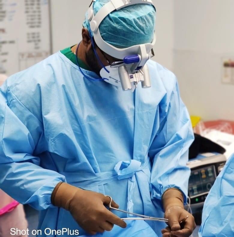 Dr. Ruthrendhra E operating while wearing surgical loupes